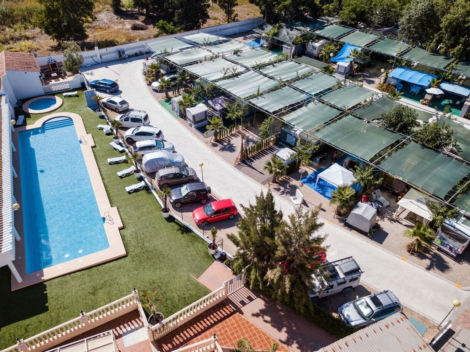 Vista aérea de camping con parcelas, piscina y zona de autocaravanas