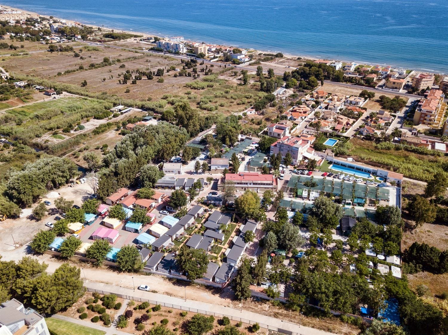 Vista aérea de camping en Dénia junto a la costa con parcelas y piscina