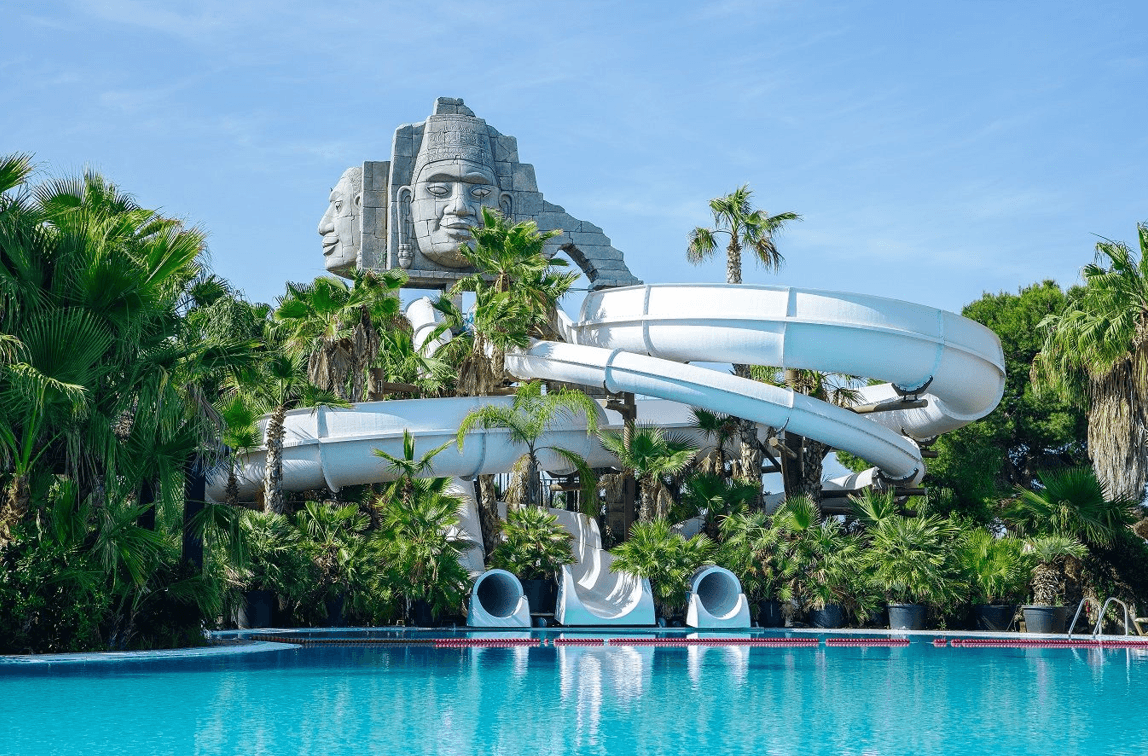 Piscina con toboganes y decoración temática tropical en camping en Alicante