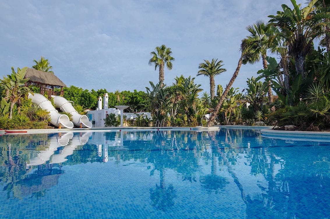 Piscina tropical con toboganes y palmeras en camping de Torrevieja