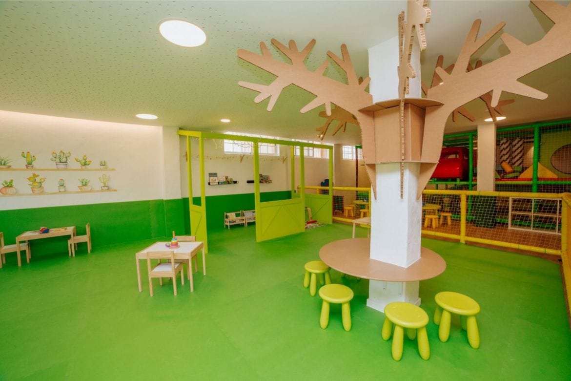 Zona infantil interior con área de juegos y mesas para niños en camping de Torrevieja