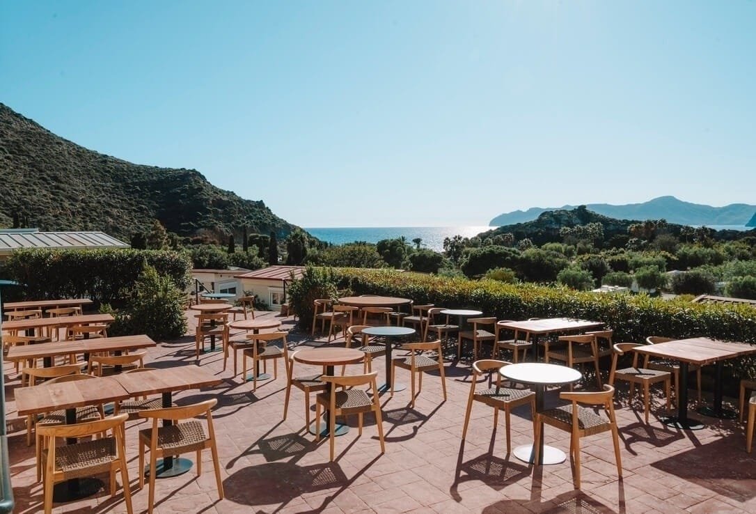 Terraza exterior con mesas y vistas al mar en camping de Murcia y alrededores