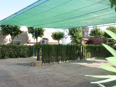 Parcela de camping con zona de sombra y setos verdes en camping de Murcia y alrededores