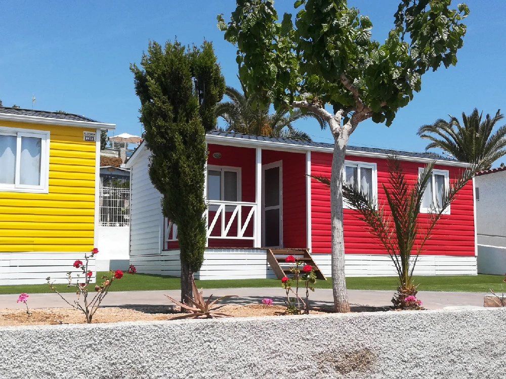 Bungalows de colores en Camping Bahía Santa Pola Alicante con zona ajardinada y palmeras