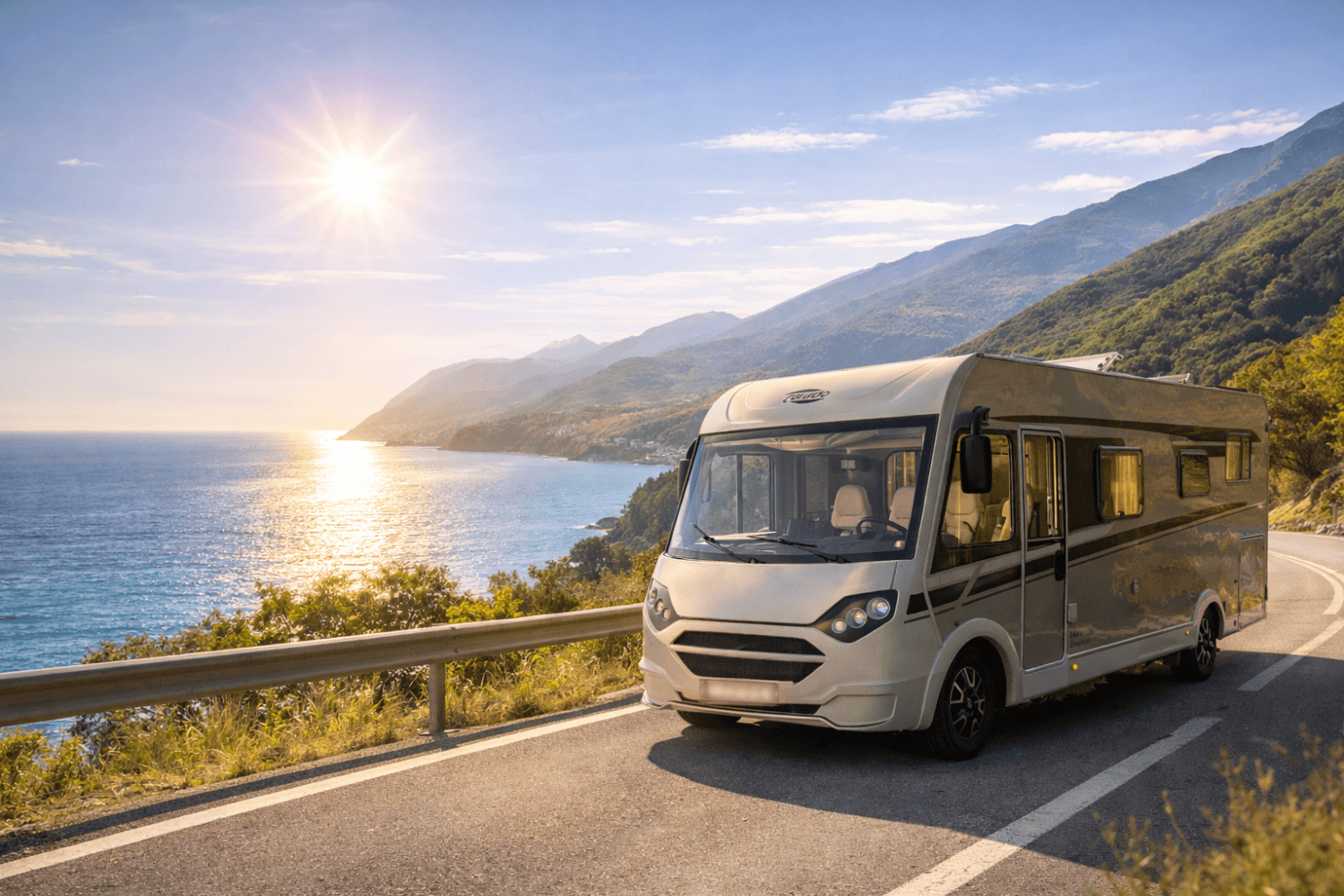 Autocaravana circulando por carretera costera con vistas al mar y montañas al atardecer