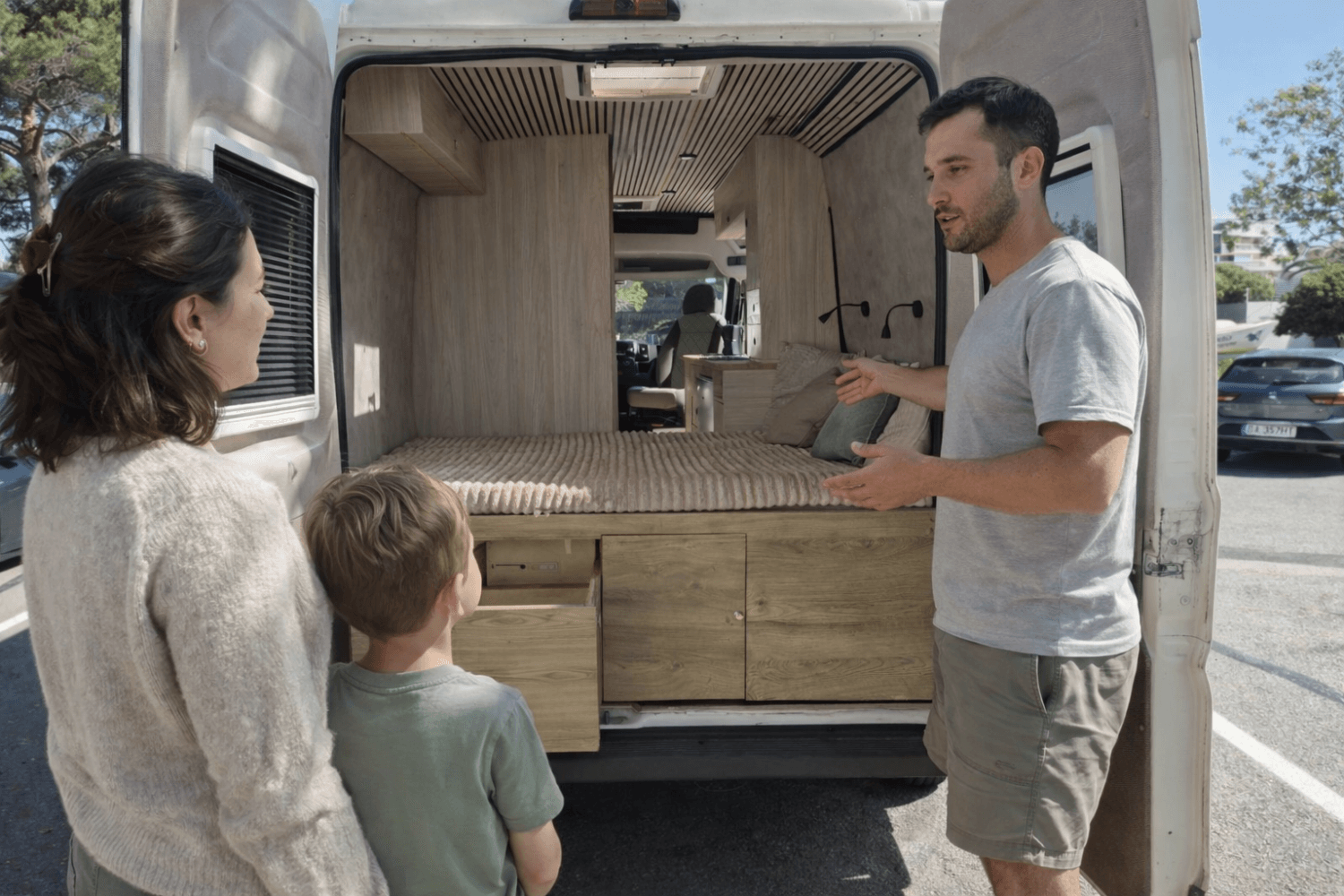 Propietario mostrando el interior y cama de una camper a madre y niño antes del alquiler