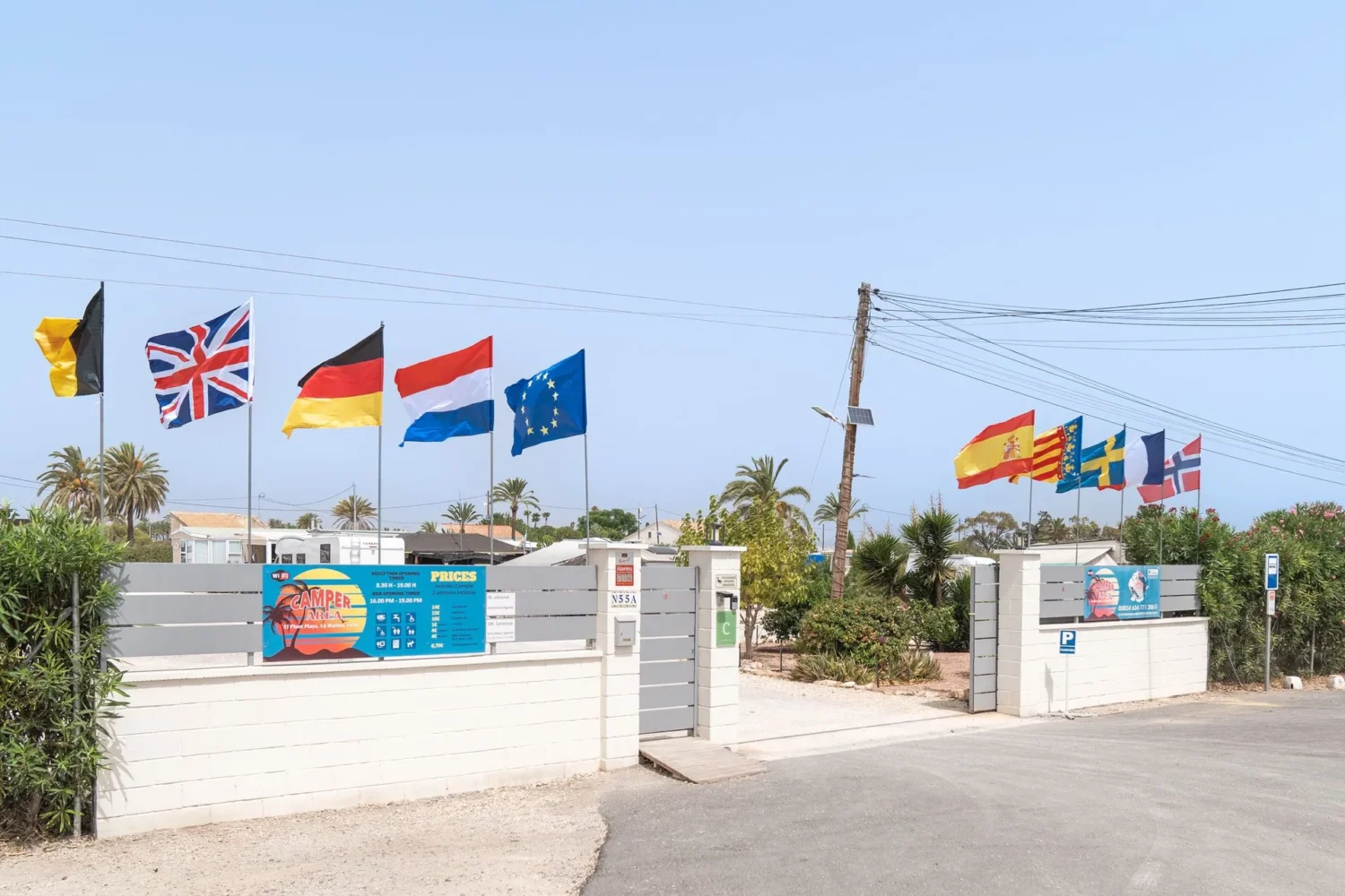 Entrada de camping con banderas internacionales y acceso para viajeros en autocaravana