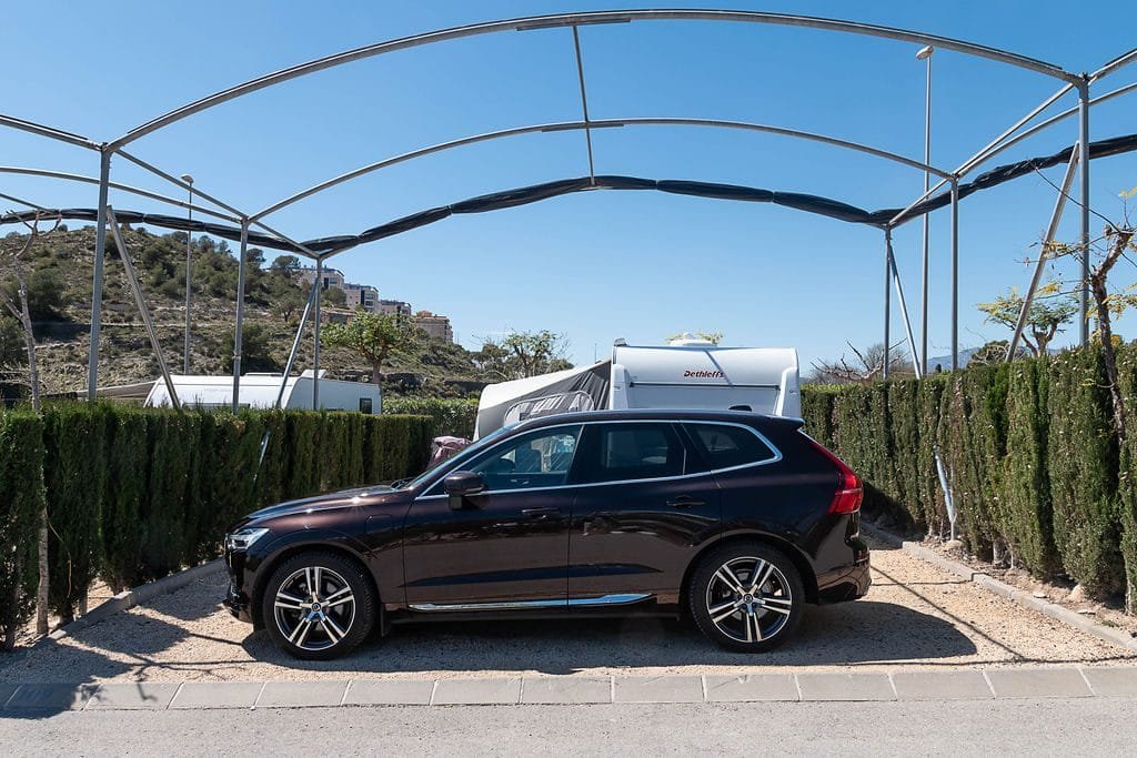 Parcela de camping con zona cubierta para estacionamiento de vehículo junto a autocaravana