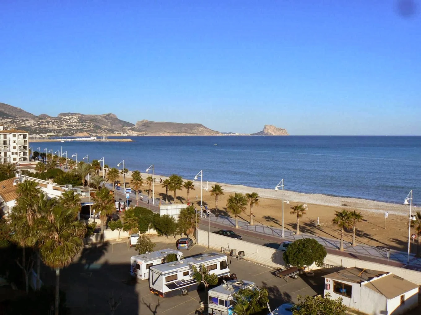 Vista aérea de camping junto al paseo marítimo y playa con palmeras y mar al fondo